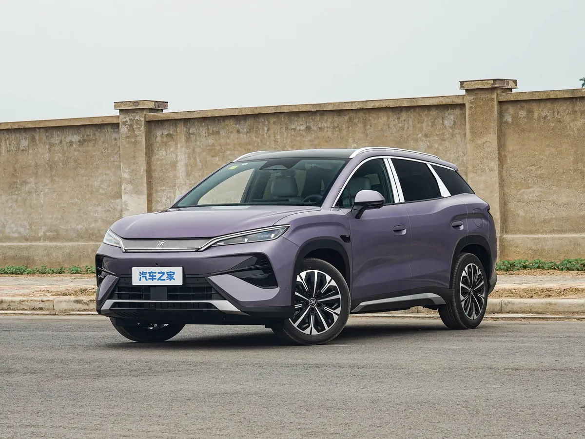 Фиолетовый BYD Song Ultra на дороге у бетонной стены, вид спереди-сбоку