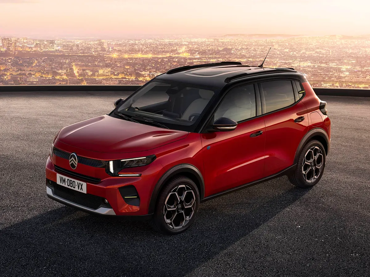 Красный компактный кроссовер Citroën с чёрной крышей на площадке на фоне города на закате