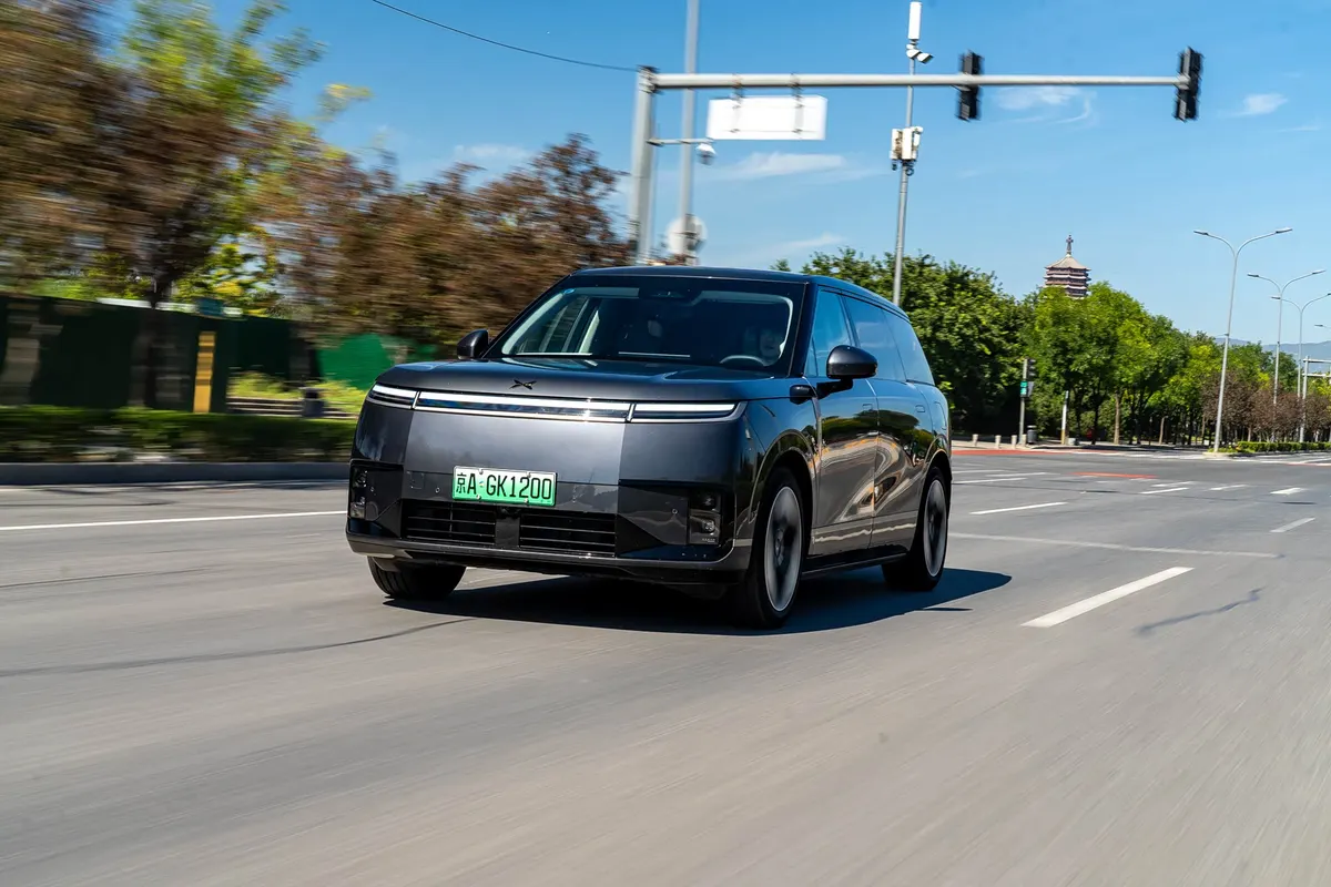 Xpeng GX едет по городской дороге в солнечную погоду, вид спереди
