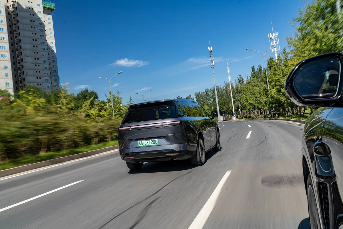 Xpeng GX сзади в потоке на городской дороге, солнечный день