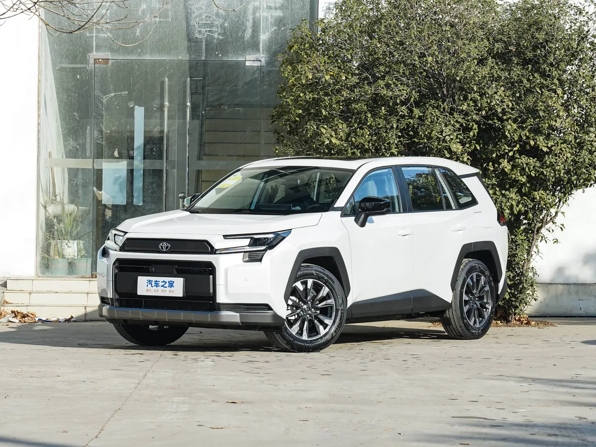 Белый кроссовер Toyota с чёрными накладками арок у стеклянной витрины и куста