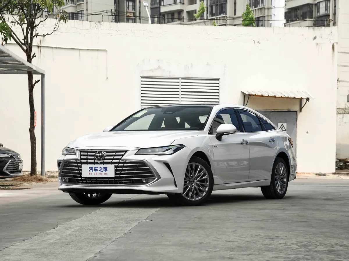 Белый седан Toyota с массивной решёткой радиатора на площадке у белого здания