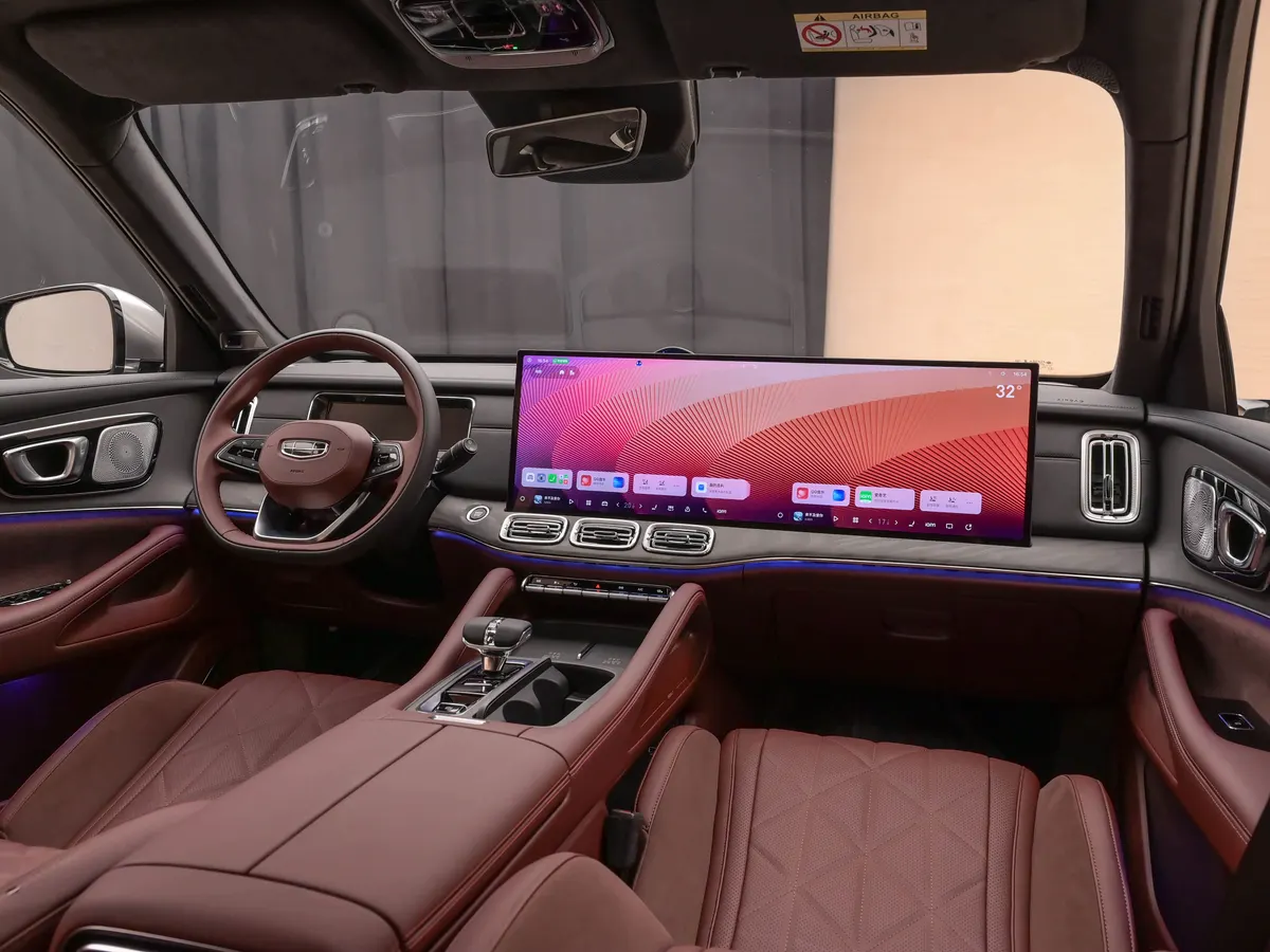 Передний ряд Geely Xingyue L PLUS сбоку: руль, широкий экран, центральный тоннель и ромбовидная прострочка сидений