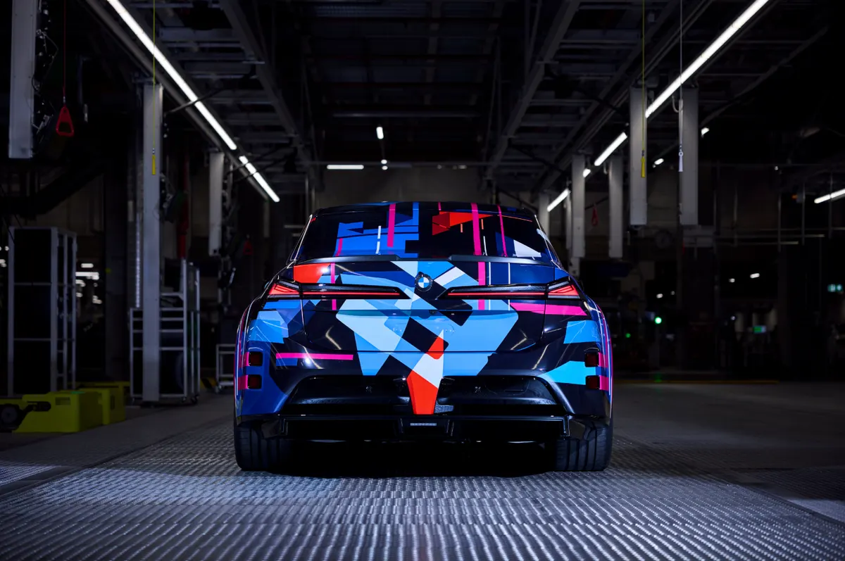 Задняя часть BMW M3 в сине-красной камуфляжной плёнке в заводском цехе