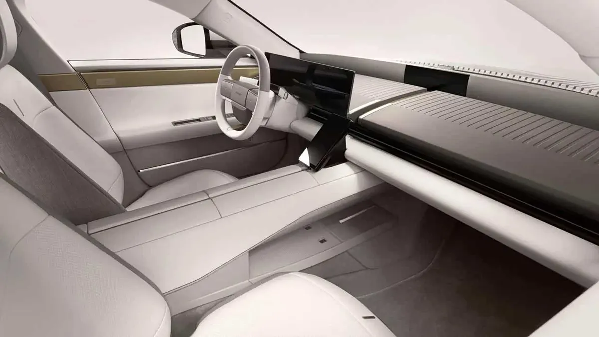 Светлый салон Jaguar Type 01 с водительской стороны: руль, широкий экран, ребристая панель