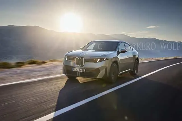 Серый BMW iX4 на скорости едет по дороге на фоне гор и низкого солнца