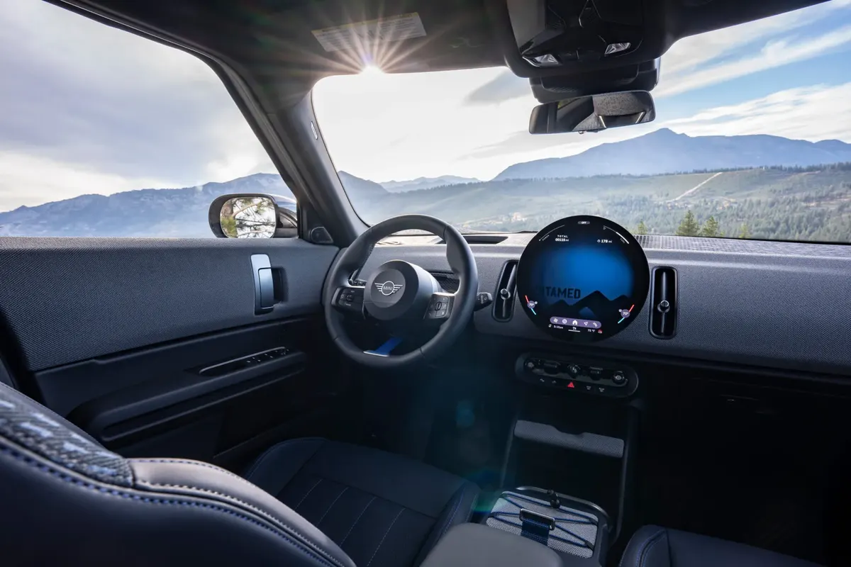 Салон MINI Countryman Untamed Edition: круглый дисплей, руль и горный пейзаж за лобовым стеклом