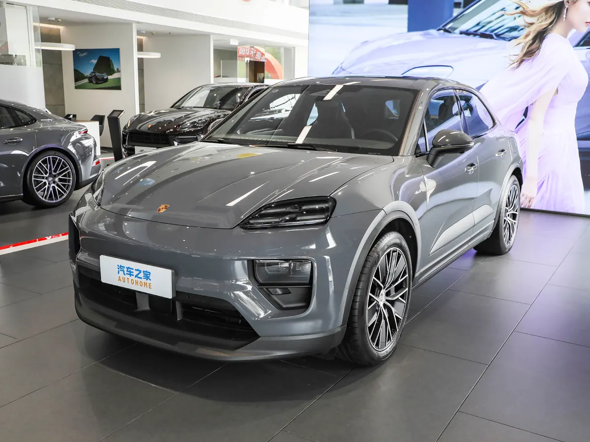 Серый электрический Porsche Macan в автосалоне, рядом видны другие автомобили Porsche