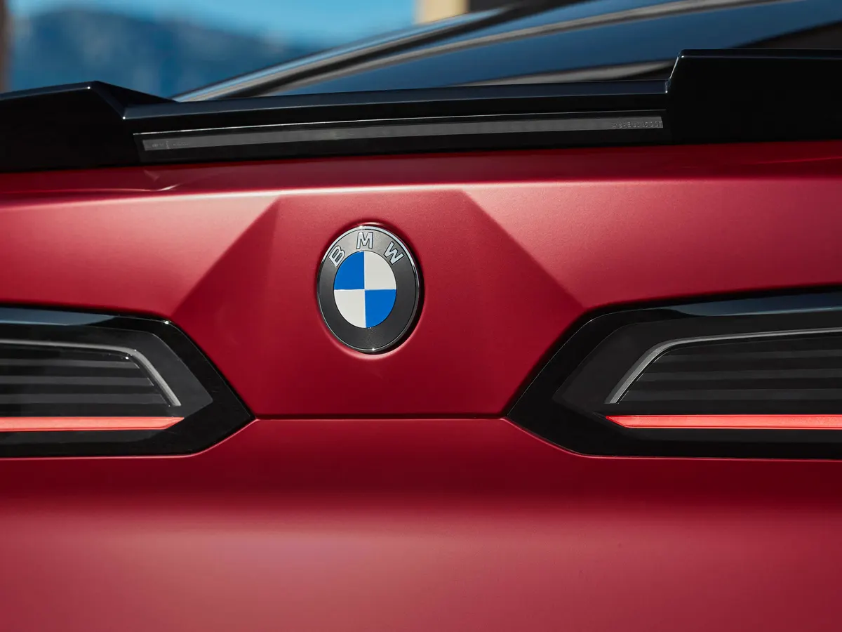 Эмблема BMW на красной крышке багажника между двумя узкими стоп-сигналами