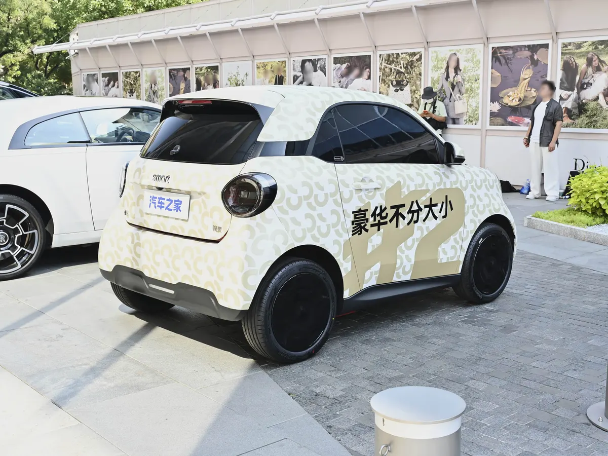 smart в камуфляжной плёнке, вид сзади сбоку, рядом припаркован белый автомобиль