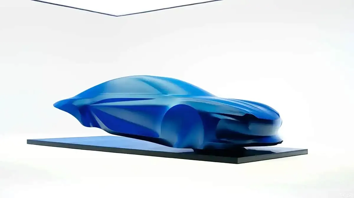 Скульптурная синяя модель кузова Alpine PS1 с плавными линиями на тёмной подставке на белом фоне