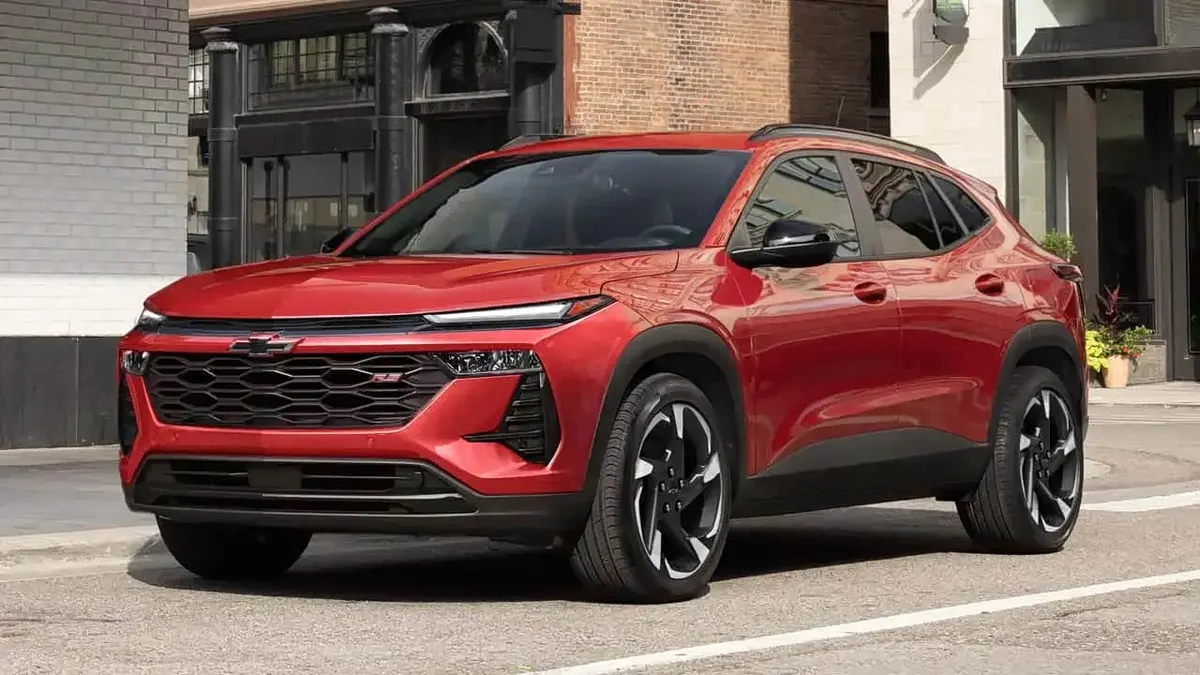 Красный Chevrolet Trax, вид спереди, на городской улице у кирпичного здания