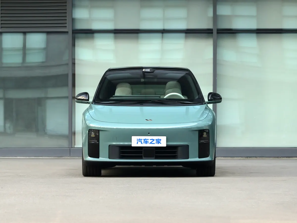Li Auto мятно-зелёного цвета, вид спереди: узкие фары, чёрная нижняя часть бампера, за машиной стеклянный фасад