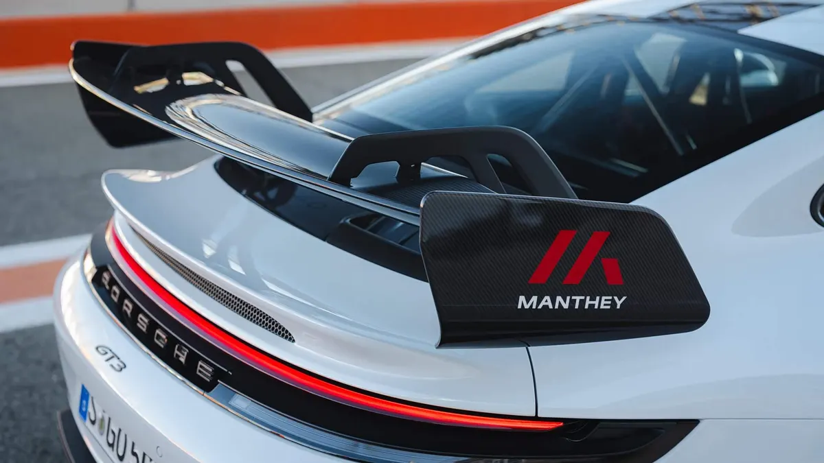 Карбоновая боковая пластина антикрыла с логотипом Manthey на белом Porsche 911 GT3 на трассе