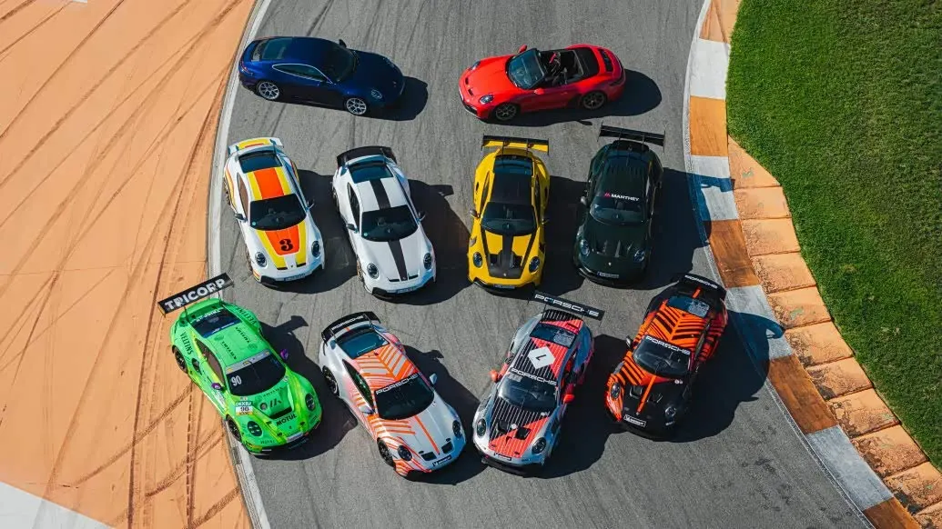 Десять разноцветных Porsche, в том числе гоночных, выстроены на изгибе трассы, вид сверху