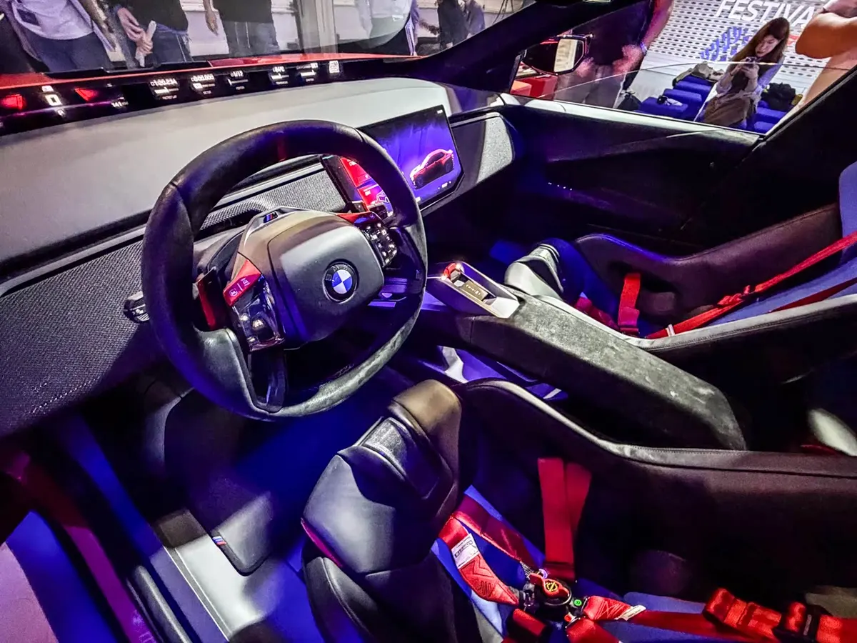 Салон BMW M Concept: руль с логотипом BMW, центральный экран и спортивные кресла с красными ремнями