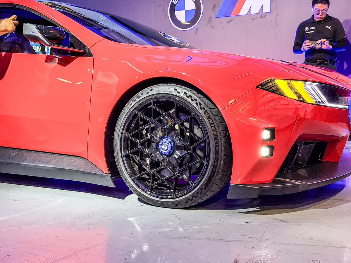 Переднее колесо красного BMW M Concept: чёрный диск с синим центральным колпачком, карбоновый порог