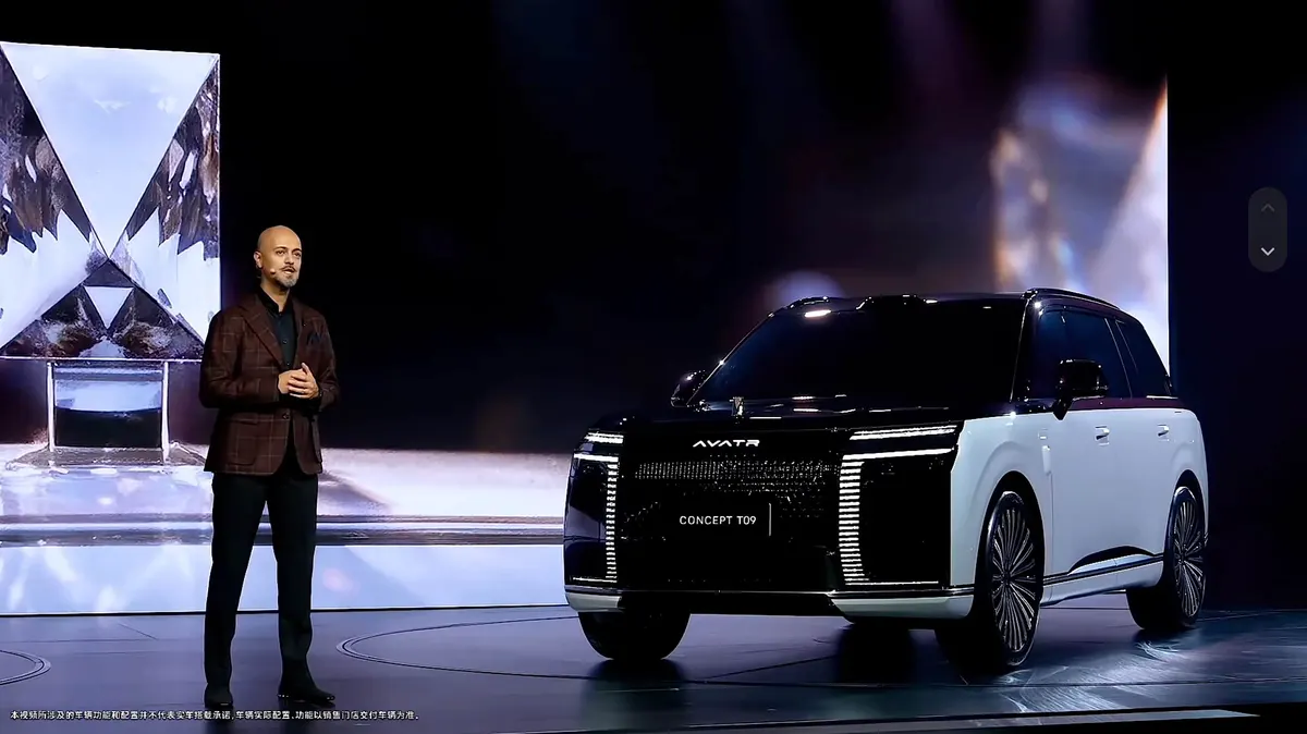 Спикер на сцене рядом с концептом Avatr Concept T09 в бело-чёрной расцветке на фоне хрустальной инсталляции