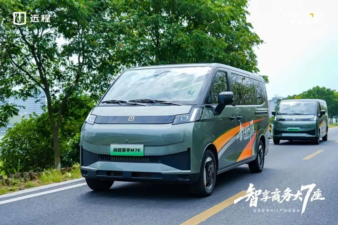 Два серо-зелёных минивэна Yuancheng Xingxiang M7E с оранжевой графикой едут по дороге среди деревьев