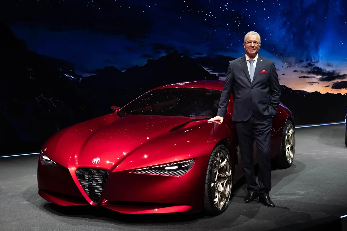 Мужчина в костюме у красного концепта Alfa Romeo Cuorerosso на фоне экрана со звёздным небом