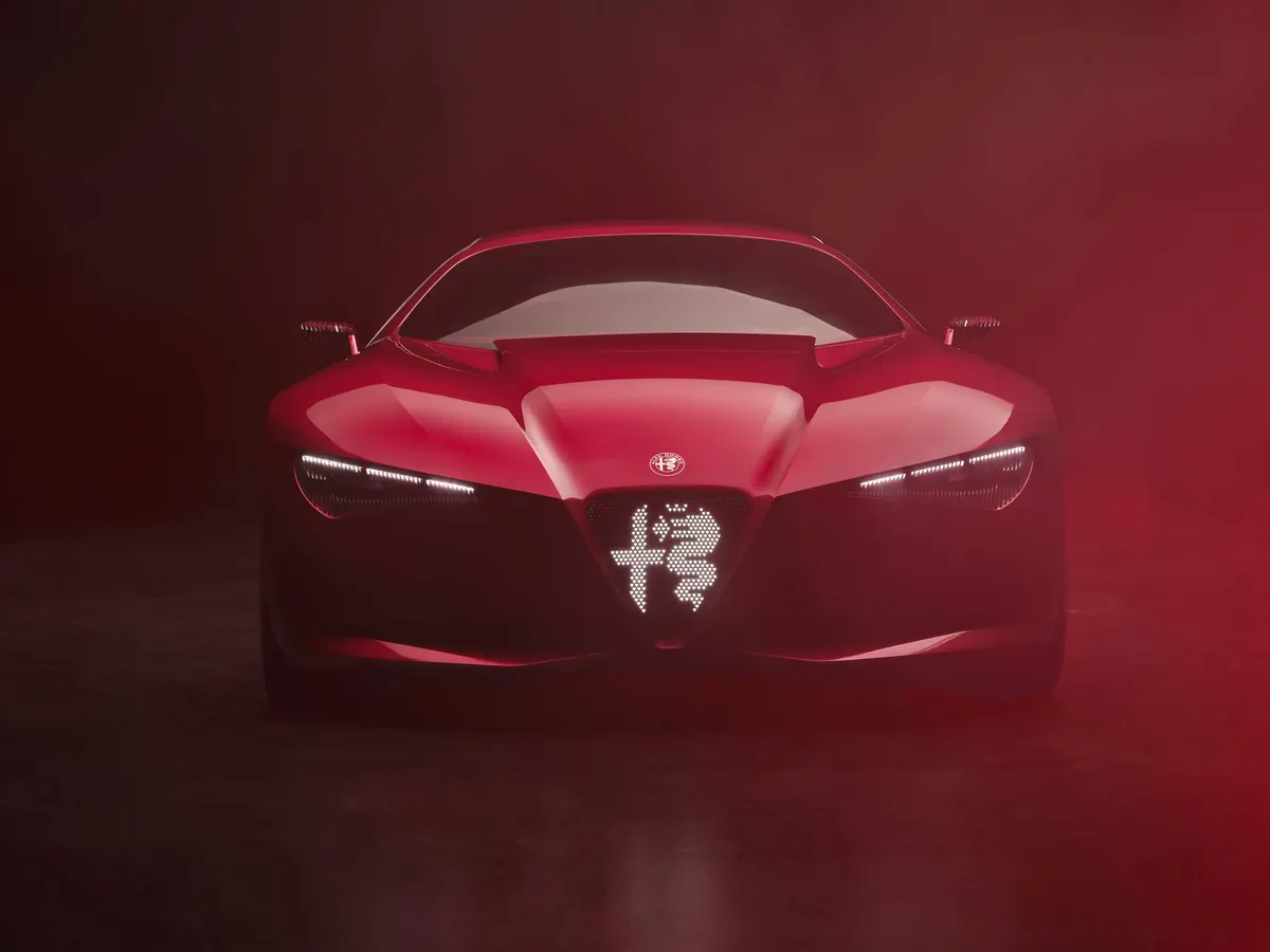 Передняя часть красного Alfa Romeo Cuorerosso: светящаяся эмблема в решётке и огни в красном тумане