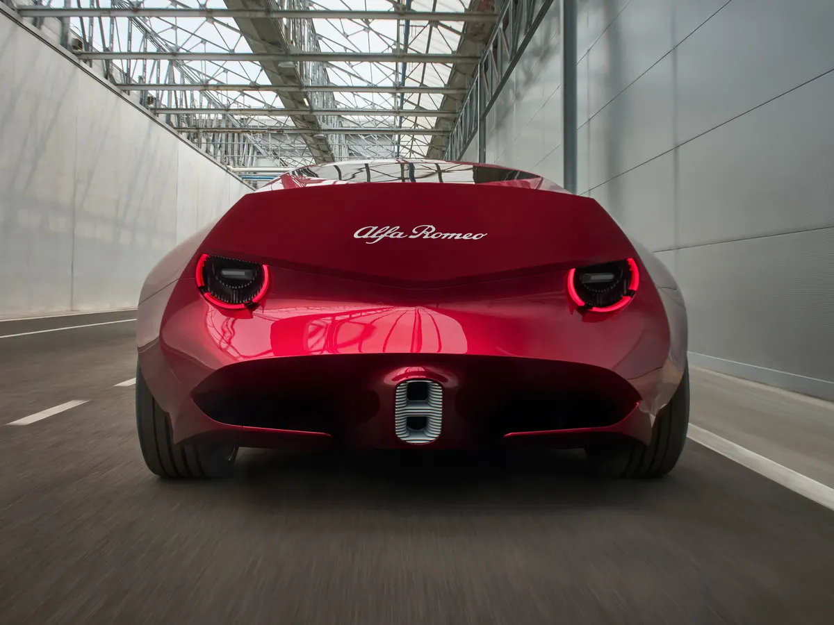Alfa Romeo Cuorerosso сзади на ходу в ангаре: круглые красные фонари и надпись Alfa Romeo