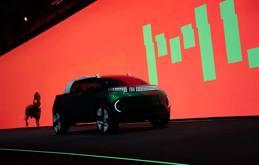 Зелёный концепт Fiat Multiplay на сцене, на фоне красного экрана сбоку стоит собака