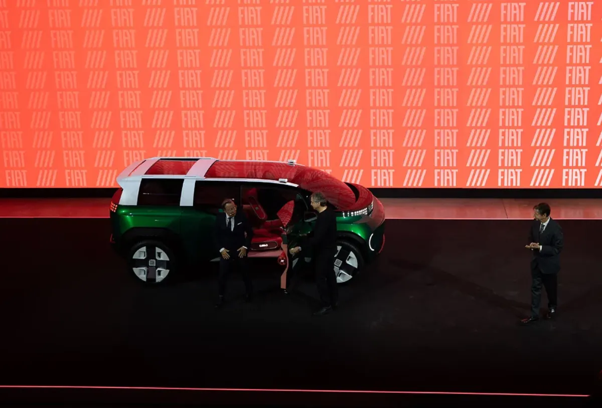 Двое мужчин у открытой двери концепта Fiat с красным салоном, рядом стоит третий; на экране логотипы Fiat