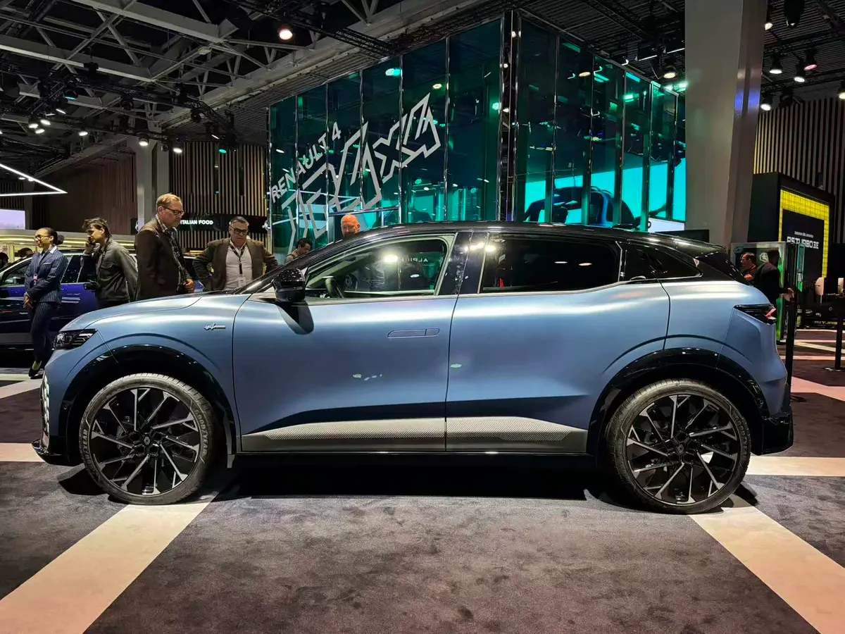 Mégane E-Tech синего цвета, вид сбоку, на выставочном стенде; рядом стоят посетители