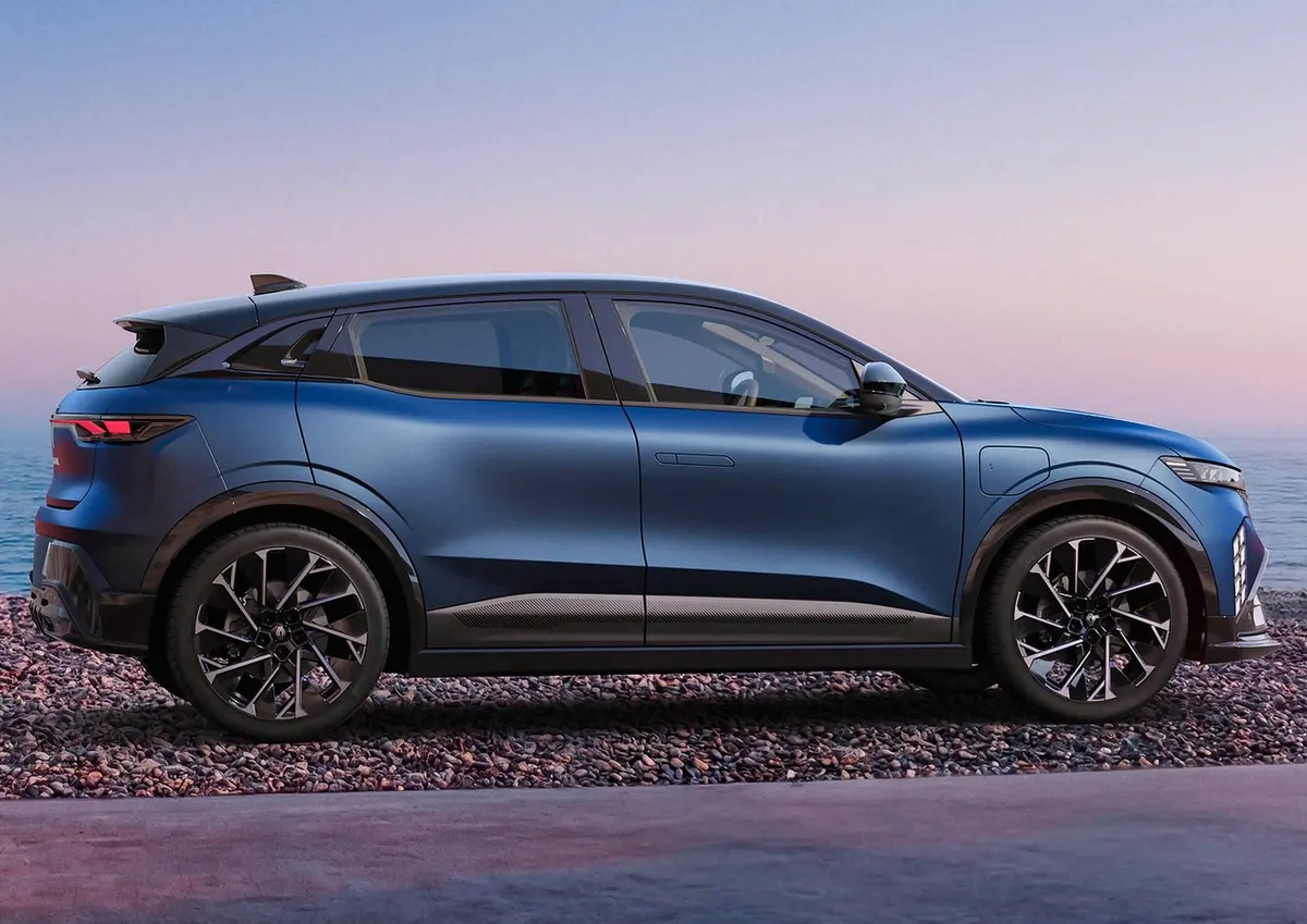 Mégane E-Tech в профиль на галечном берегу, на фоне моря в сумерках