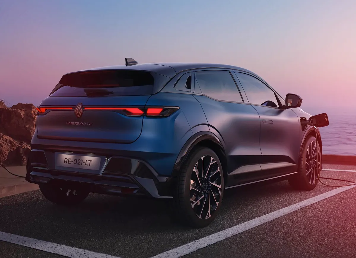 Mégane E-Tech сзади, подключённый к зарядному кабелю на парковке у моря