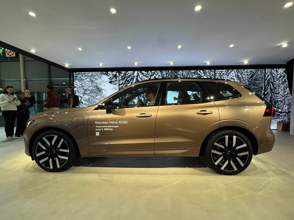 Volvo XC60 бронзового цвета сбоку на стенде с надписью об электрическом запасе хода до 200 км