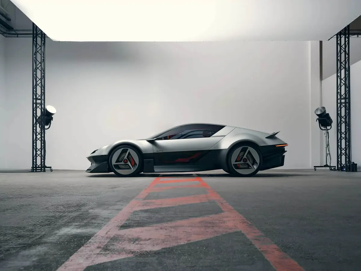 Концепт Alpine A310 VISION в профиль в студии: по бокам стойки с прожекторами, на полу красная разметка