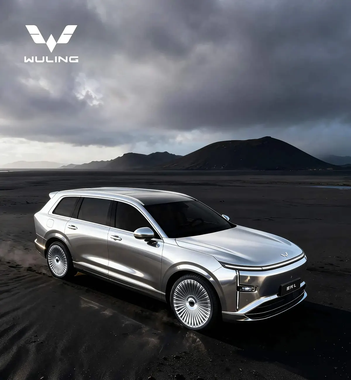 Wuling Starlight L в серебристом цвете, вид спереди-сбоку, на фоне тёмных гор и пасмурного неба
