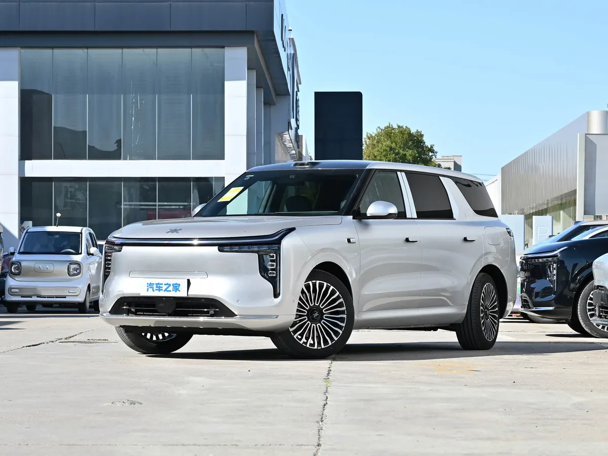 Серебристый IM LS8 NEO спереди в три четверти на площадке у автоцентра, светящаяся полоса на передней части