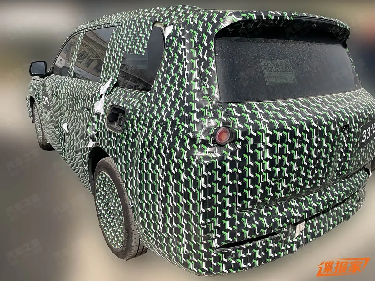Прототип Leapmotor в камуфляже сзади-сбоку: лючок на заднем крыле, круглый фонарь, стекло