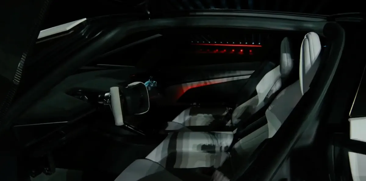 Тёмный салон Roadster: два светлых сиденья, руль-штурвал, красная подсветка на панелях