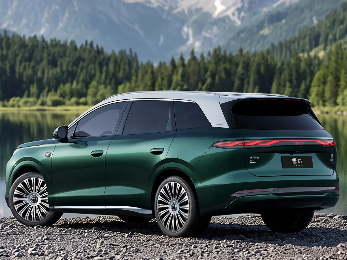 Тёмно-зелёный BYD Tang сзади-сбоку на берегу озера на фоне леса и гор