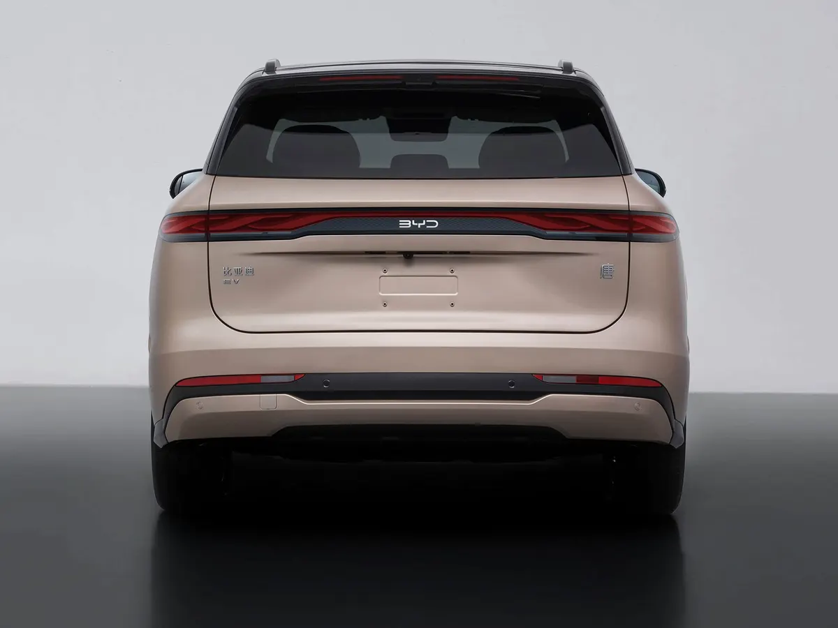 BYD Tang в бежевом цвете сзади: сплошная полоса фонарей с логотипом BYD, студийный фон