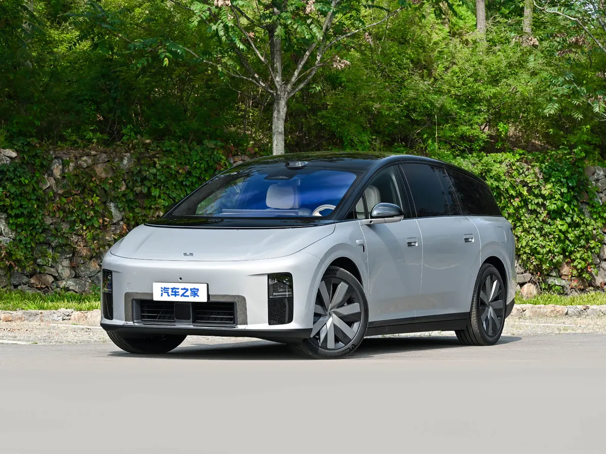 Серебристый минивэн Li Auto с чёрной крышей на дороге у каменной стены с зеленью