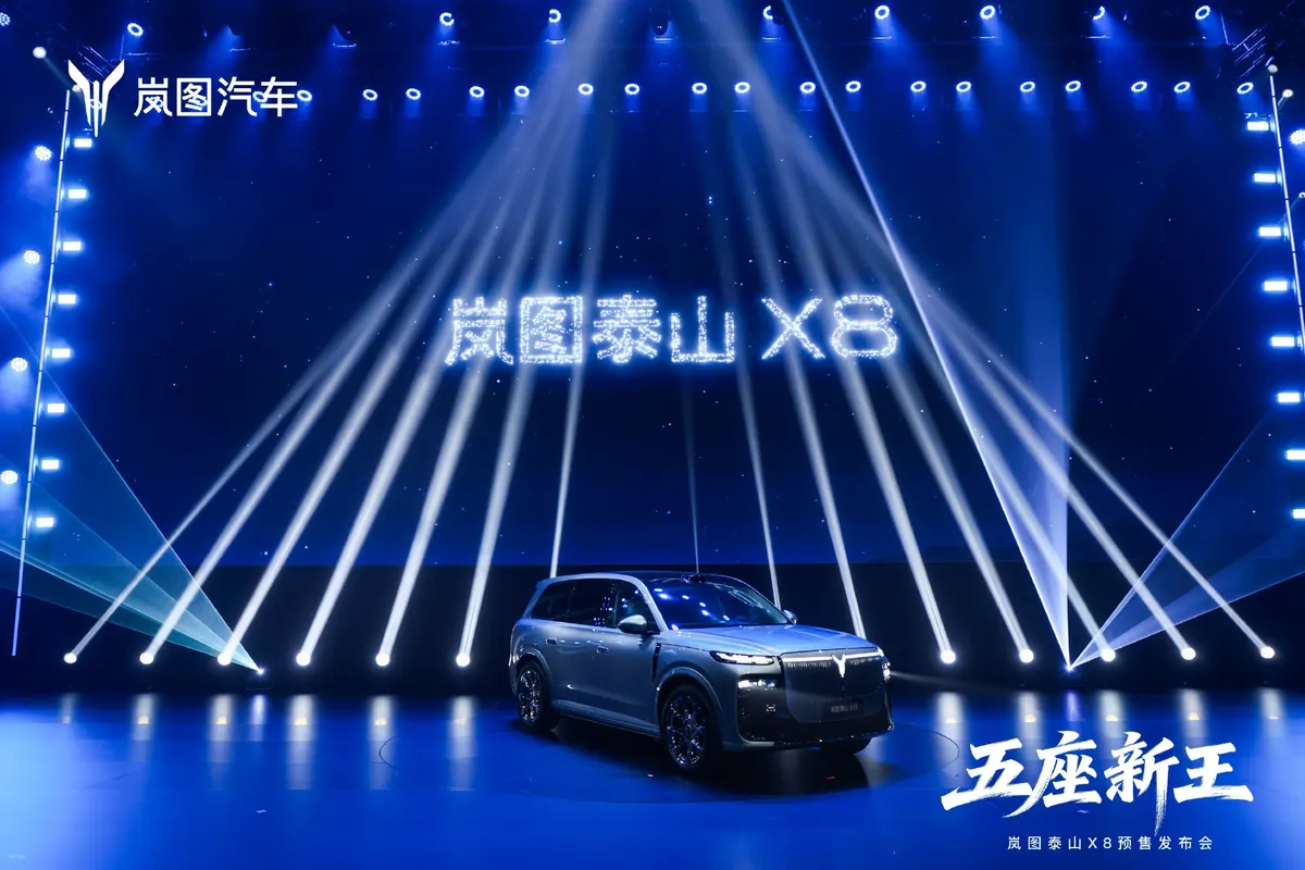Voyah Taishan X8 на сцене в синей подсветке: лучи света расходятся веером, на экране — название модели