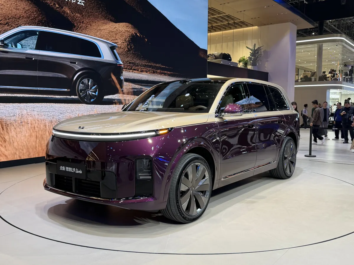 Li Auto L9 Livis в фиолетово-золотистом цвете на круглой платформе выставочного стенда, вид спереди спереди-сбоку