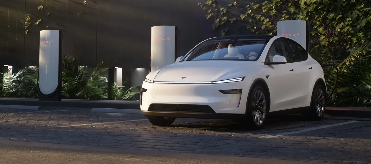 Белый электрокроссовер Tesla на парковке у зарядных станций Tesla среди зелени