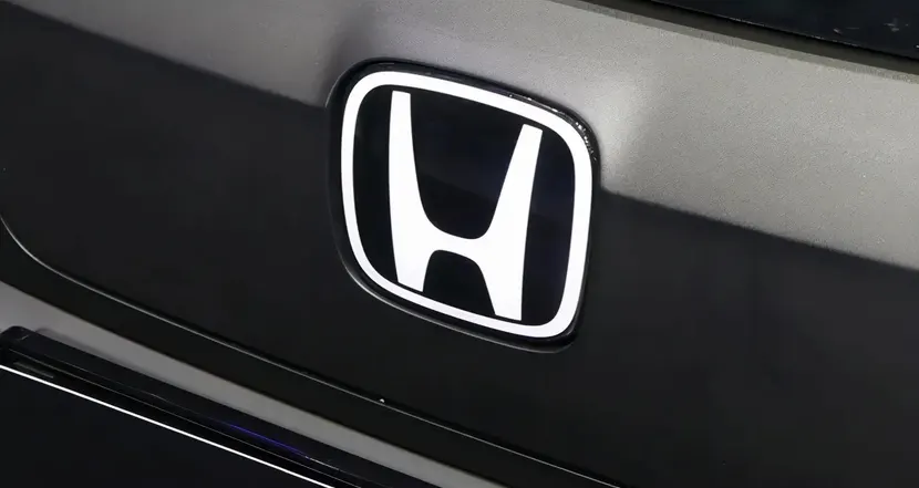 Эмблема Honda с буквой H на тёмной крышке багажника автомобиля крупным планом