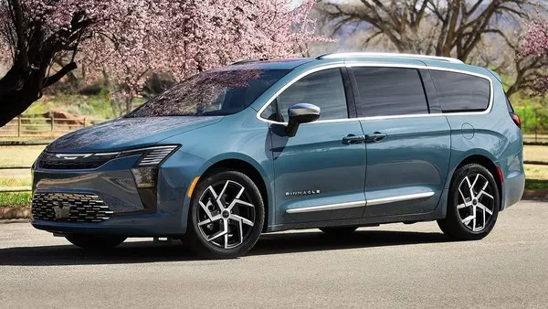 Сине-серый минивэн Chrysler стоит на дороге на фоне цветущих розовых деревьев