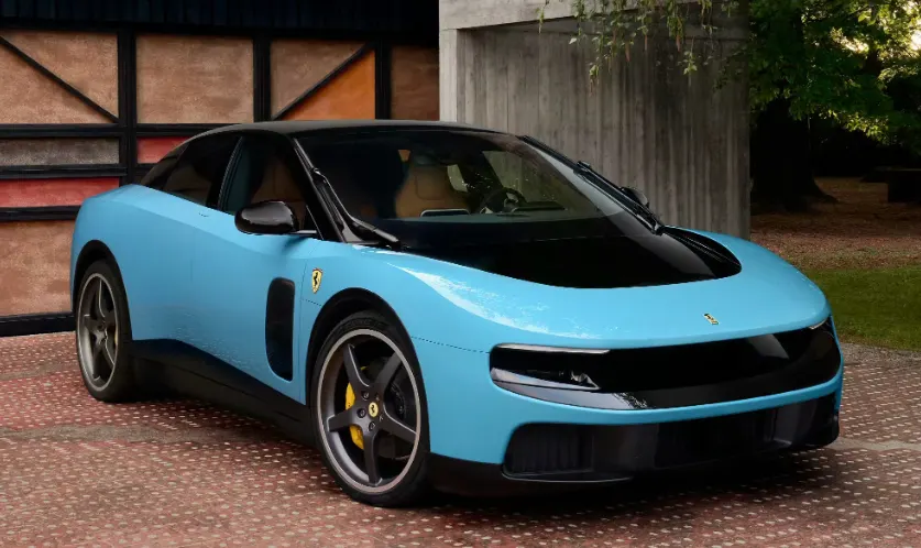Голубой Ferrari LUCE с чёрной крышей и жёлтыми суппортами, вид спереди, на фоне бетонной стены