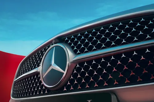 Решётка радиатора Mercedes-Benz с трёхлучевой звездой и узором из звёздочек на фоне голубого неба