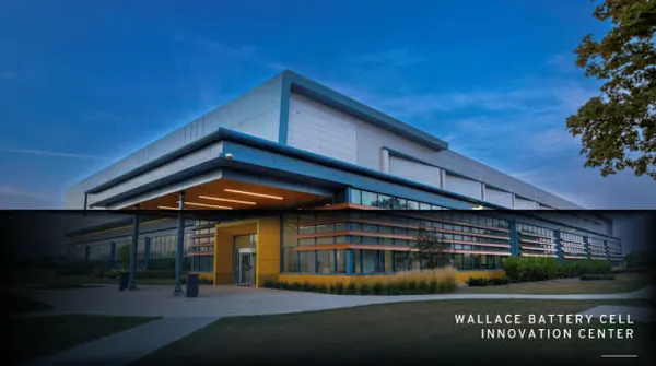 Здание центра Wallace Battery Cell Innovation Center в сумерках: стеклянный фасад с жёлтыми и синими акцентами
