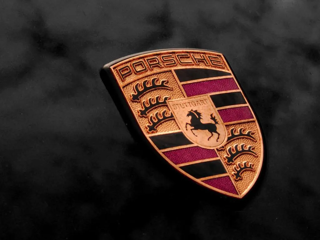 Герб Porsche с чёрным конём и надписью Stuttgart, красные и чёрные полосы, тёмный фон