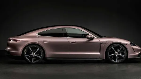 Четырёхдверное купе Porsche в розово-бежевом металлике, вид сбоку, на тёмном студийном фоне